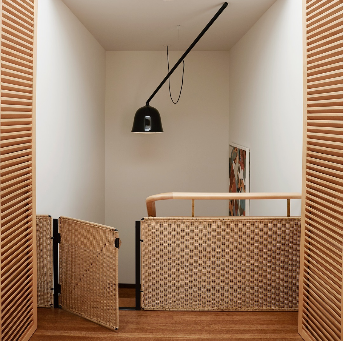 
A thoughtfully designed stairwell featuring a sleek, architectural-style pet gate that blends with the home's neutral palette, alongside secured cords and non-toxic plants, illustrating how safety measures can coexist with elevated interior design
